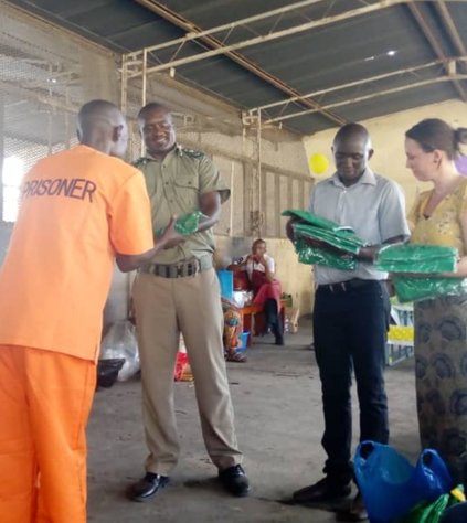 Anne Egelund and Obed Kunda (Ubumi) and the Officer in Charge hand out T-shirts to the volunteers